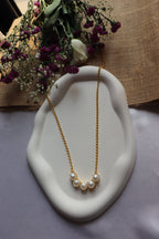 Pearl necklace on a white dish with flowers in the background